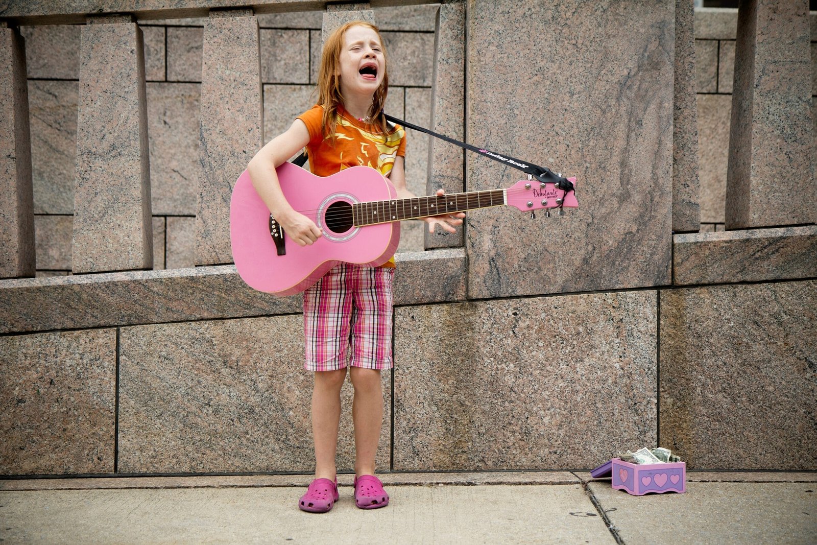 girl playing guitar near wall